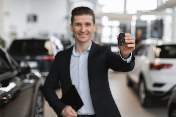 Onnistunut nuori myyntimies osoittaa auton avain kameran auto jälleenmyyntisopimuksen, valikoiva keskittyä. Happy Millennial manageri myy autoja showroom. Ajoneuvojen paikallinen jakelu - Valokuva, kuva
