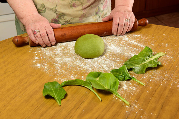 Бабушка на кухне на коленях раскладывает тесто для лапши. - Фото, изображение