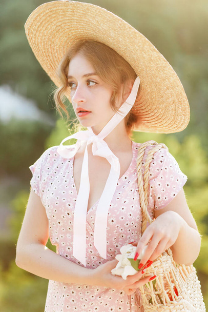 Κοντινό πορτραίτο μιας γλυκιάς ξανθιάς με ψάθινο καπέλο στο ηλιοβασίλεμα - Φωτογραφία, εικόνα