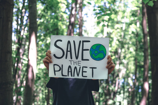 Plakát ve výzvě k záchraně planety v ženských rukou v lese, koncept péče o přírodu, čištění, recyklaci a ekologii. - Fotografie, Obrázek