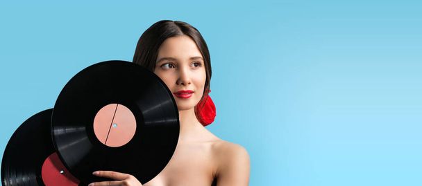 Beautiful make up woman face over a blue background holding with her hands vinyl music records, music concept. . High quality photo - Photo, Image
