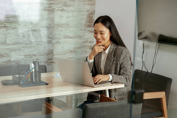 Souriant asiatique femme travail ordinateur portable assis dans la salle de réunion dans le bureau. Photo de haute qualité - Photo, image