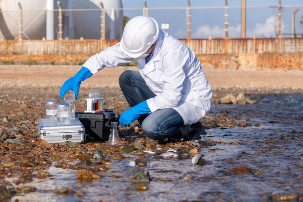 scientist wearing protective  uniform and glove under working water analysis and water quality by get waste water to check case in laboratory is environment pollution problem concept - Foto, imagen