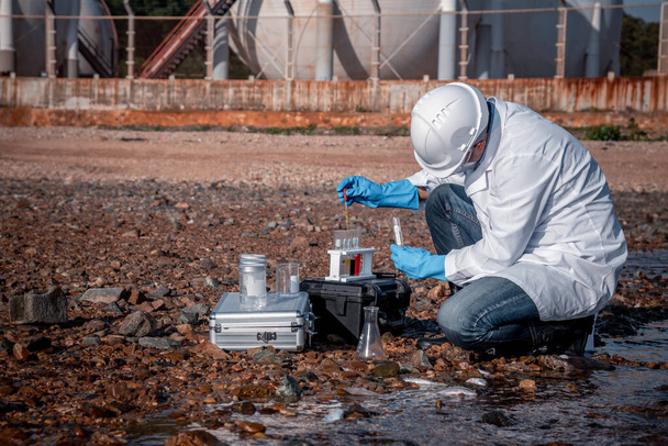 scientist wearing protective  uniform and glove under working water analysis and water quality by get waste water to check case in laboratory is environment pollution problem concept - Fotoğraf, Görsel