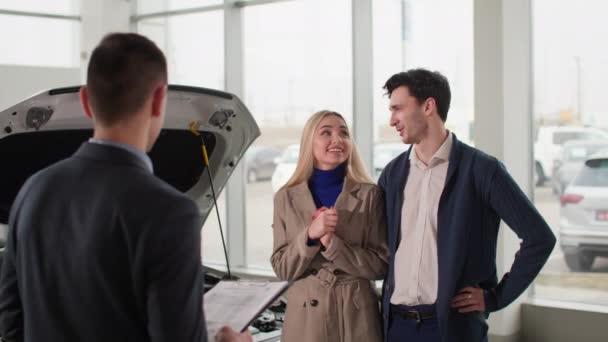 automobilové centrum, muž a žena mluví s prodejcem aut a nákupním manažerem v prodejním centru - Záběry, video