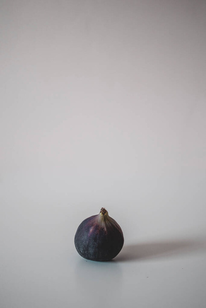 Une figue fraîche et mûre sur la table sur fond gris. Décor minimalisme.  - Photo, image