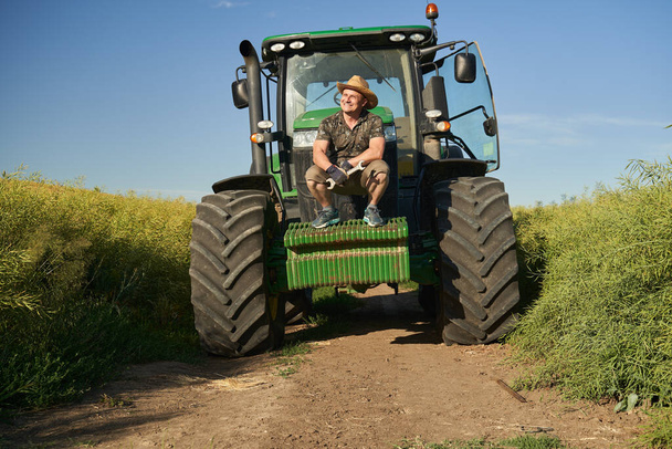 Farmer with his tractor in the rapeseed field - Φωτογραφία, εικόνα