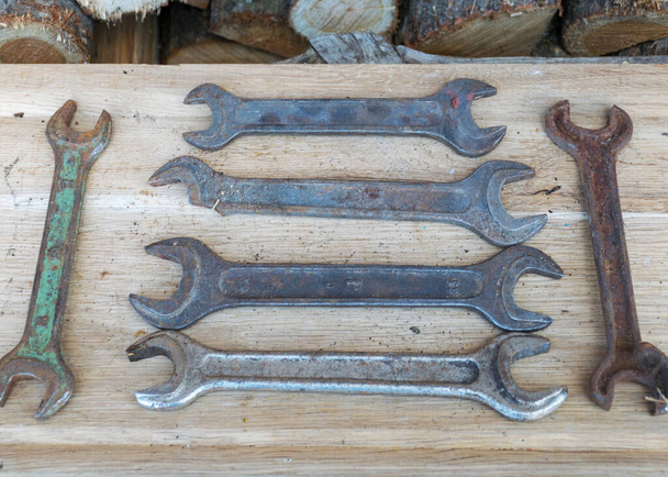 Antique wrenches on a wooden background, rusty tools, metal waste, scrap metal, wrench collection - Foto, imagen