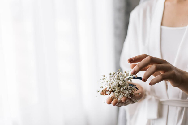 The bride holds a boutonniere in her hands. Horizontal photo - Valokuva, kuva
