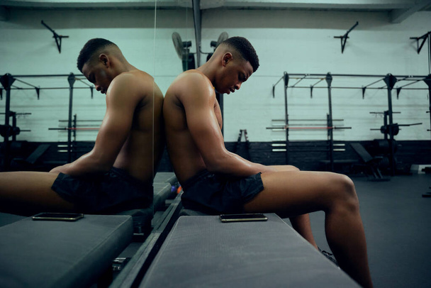 African American male athlete resting in the gym after a hard cross training. Shirtless mixed race male sitting down after exercising. High quality photo - Foto, Imagem