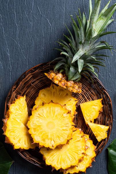 Top view of fresh cut pineapple with tropical leaves on dark blue background. - Fotó, kép