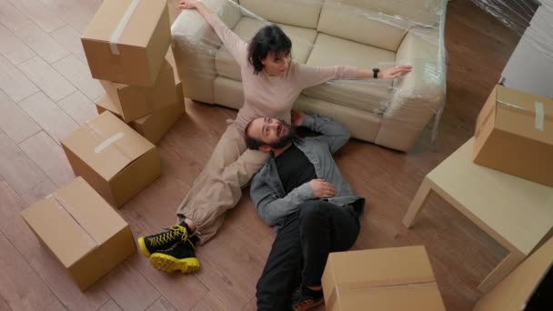 Životní partneři sedí na podlaze bytu poté, co se k sobě nastěhovali, připravují se vybalit skladovací boxy a zdobit nábytkem. Jsem nadšený z budoucí rodiny. Horní pohled. - Záběry, video