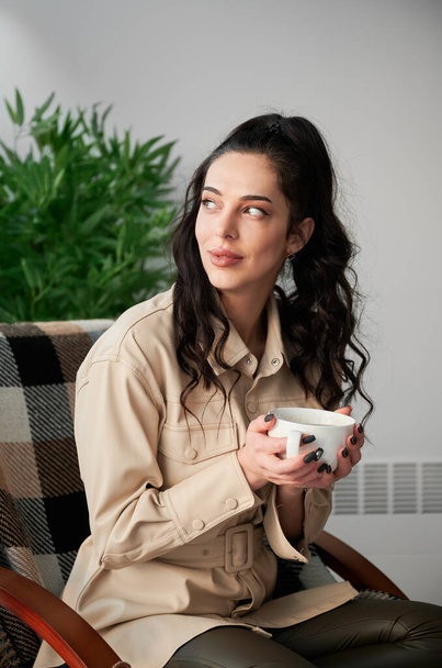 Close up young woman drinking hot tea, enjoying weekends inside contemporary barn house. - Foto, imagen