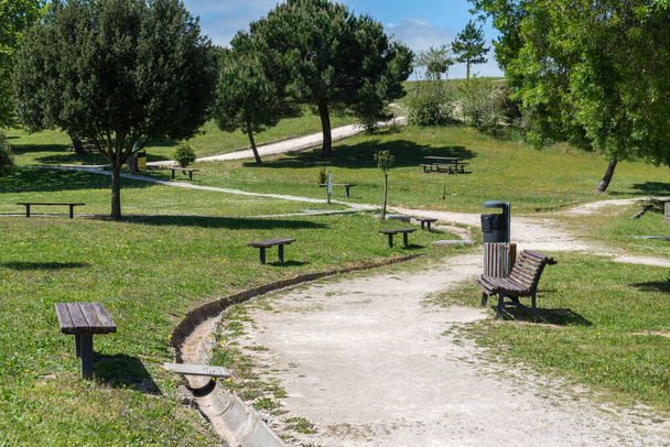 A scenic view of path amid the green park with wooden benches surrounded by trees in Loures, Portugal - Fotografie, Obrázek