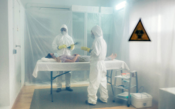 Bakteriyolojik koruma alanındaki doktorlar sahra hastanesindeki bir sedyede yatan hastaya tıbbi muayene yapıyorlar. - Fotoğraf, Görsel