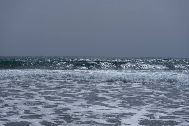 A scenic view of wavy and foamy sea under the gloomy sky - Fotó, kép