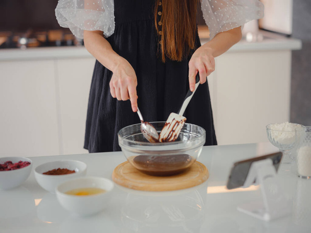 bakery, food and people concept. Beautiful woman cook chocolate cake in kitchen room. Young woman smiling, loves to cook in a beautiful modern kitchen. - Zdjęcie, obraz