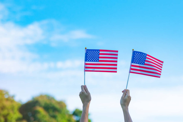 hand holding United States of America flag on blue sky background. USA holiday of Veterans, Memorial, Independence ( Fourth of July) and Labor Day concept - Photo, Image