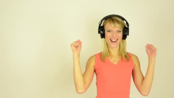 Mujer atractiva joven escucha música con auriculares y se alegra - estudio
 - Metraje, vídeo