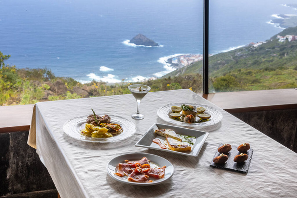 Various dishes on a restaurant table with a great view of a sea - Фото, изображение