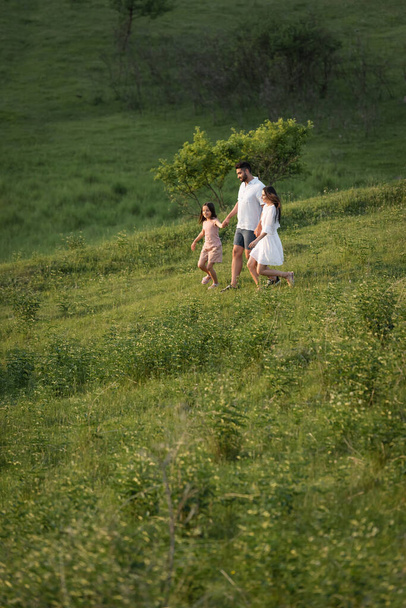 family holding hands while walking on picturesque hill in countryside - Фото, зображення