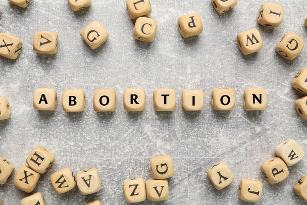 Word Abortion made of wooden cubes on grey background, flat lay - Φωτογραφία, εικόνα