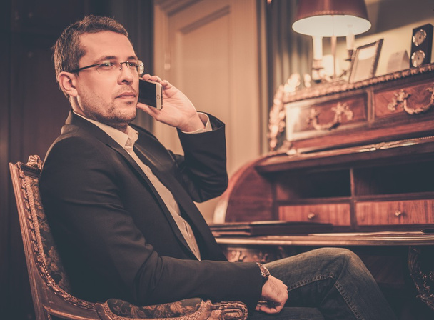 Homme confiant d'âge moyen avec téléphone portable dans un intérieur de luxe
  - Photo, image