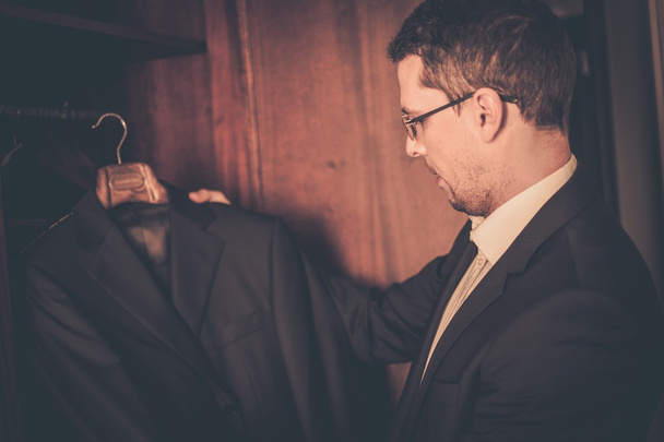 Μεσήλικας άνδρας λαμβάνοντας κοστούμι από την ντουλάπα  - Φωτογραφία, εικόνα