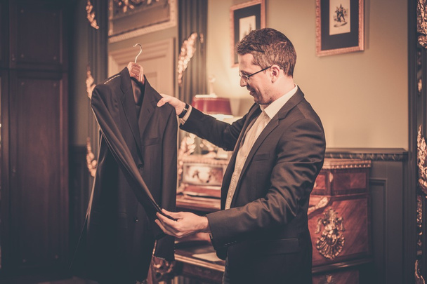 Man van middelbare leeftijd kijken naar pak op een hanger  - Foto, afbeelding