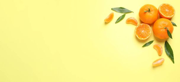 Flat lay composition with fresh ripe tangerines and leaves on light yellow background, space for text. Banner design - Foto, afbeelding