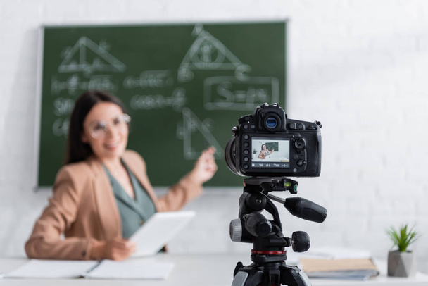 Digital camera near blurred teacher in classroom  - Fotografie, Obrázek