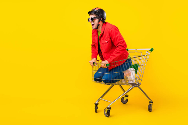 Full length body size view of attractive cheery guy inside cart having fun copy space isolated on bright yellow color background. - Фото, изображение