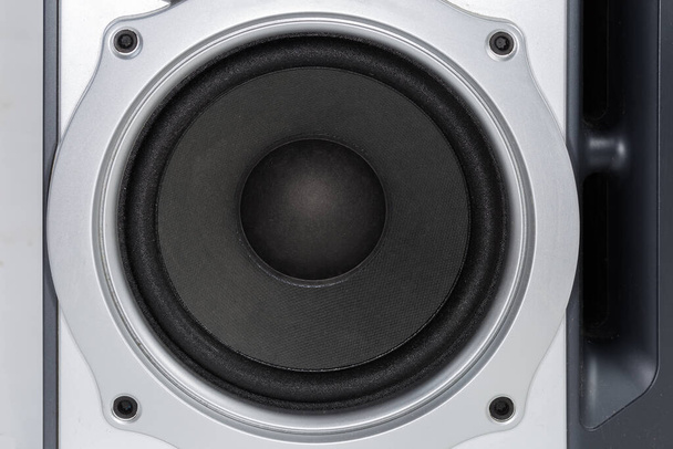 Woofer with black diffuser on the silvery plastic front panel of the home loudspeaker close-up - Fotó, kép