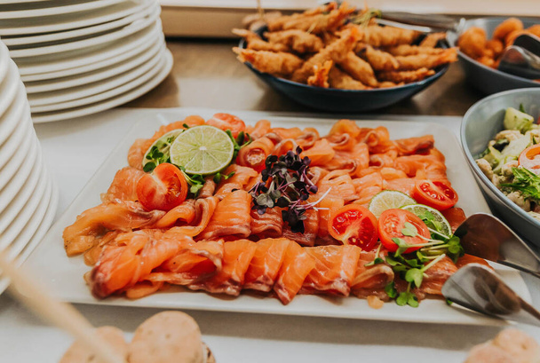 A plate full of salmon pieces served with lime slices and tomatoes - Photo, image
