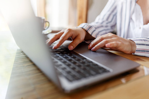 Zblízka obrázek ženy ruce psaní na klávesnici notebooku a surfování na internetu na kancelářském stole, on-line, pracovní, obchodní a technologické, internetové sítě komunikační koncept.  - Fotografie, Obrázek
