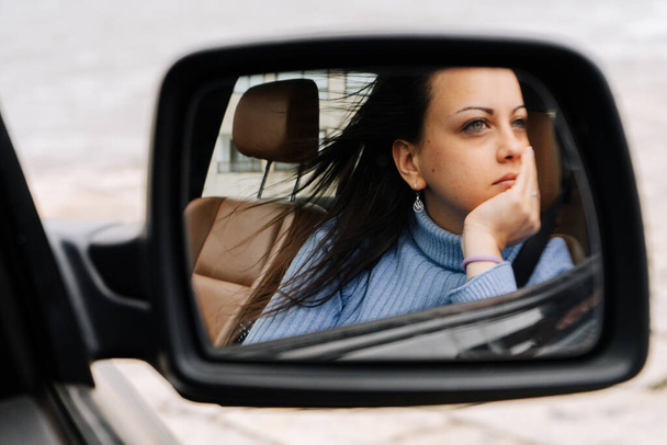 Portrait miroir d'une jeune femme assise sur le siège passager d'une voiture - Photo, image