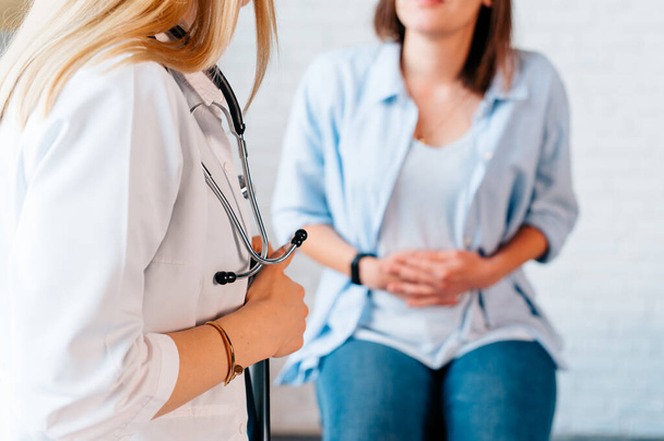 a woman in consultation with a doctor with abdominal pain. It is a painful menstrual period or bladder. And ectopic pregnancy. Immediate treatment immediately. - Photo, Image