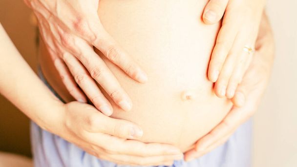 Έγκυος με χέρια κοιλιάς. Ευτυχισμένη εγκυμοσύνη, γυναίκα και άντρας αγκαλιάζουν έγκυο κοιλιά. Έννοια της εγκυμοσύνης, μητρότητας, προσδοκία για τη γέννηση του μωρού - Φωτογραφία, εικόνα