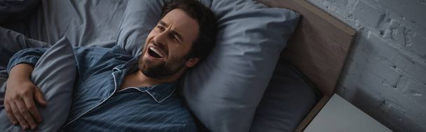Top view of man in pajama yawning on bed in morning, banner  - Foto, Imagen