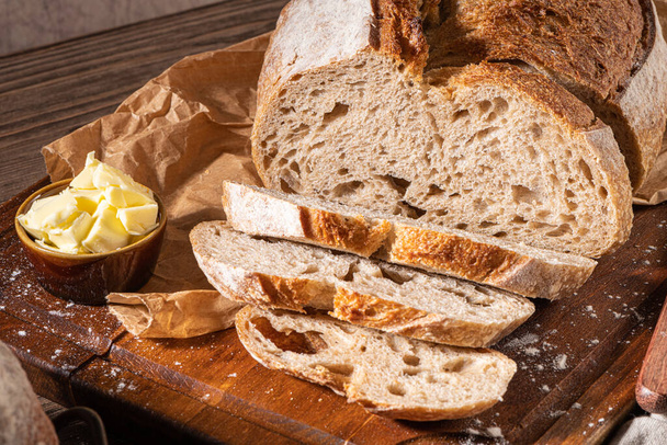 Vers ambachtelijk gebakken tarwe en roggebrood, landbrood. Eenvoudig brood met boter voor breekvast - Foto, afbeelding