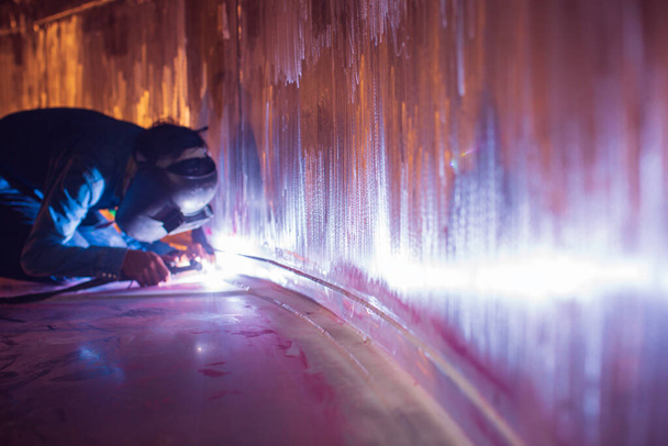 Saldatura argon lavoratore maschio riparato metallo è scintille saldatura costruzione industriale serbatoio di olio inossidabile all'interno di spazi ristretti. - Foto, immagini