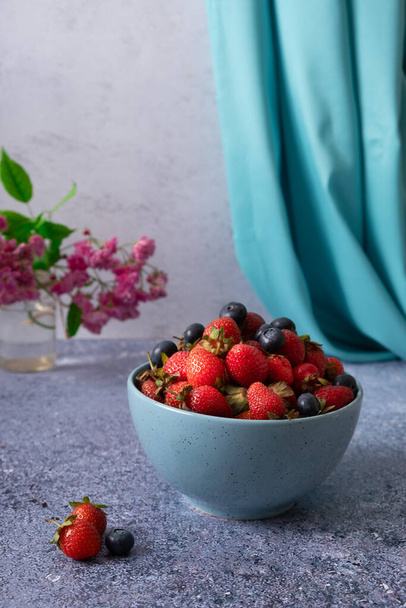 Fraises rouges mûres de jardin dans l'assiette sur la table en pierre sombre. - Photo, image