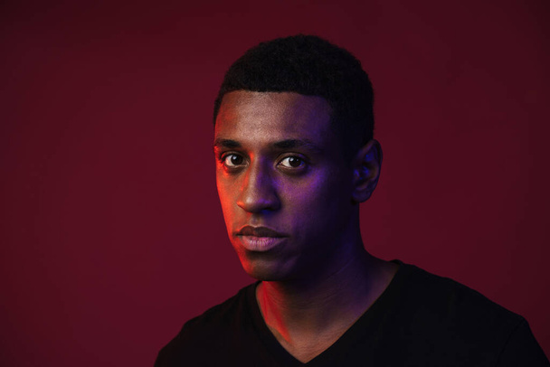 Young black man posing and looking at camera isolated over red wall - Foto, Imagem