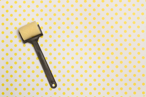 Un petit rouleau de peinture sur un fond à pois jaunes avec espace de copie - Photo, image