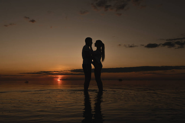 Romantic couple on the background of sunset near the ocean. Sunset walk along the ocean - Foto, Imagen