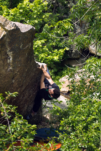 Doğal arazide kaya parçalarına ayrılan güçlü bir adam kayaya tırmanır, spor için doğaya gider, üstesinden gelmek için çabalar. - Fotoğraf, Görsel