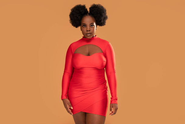 Beautiful african Woman posing in red mini dress, looking at the camera. Afro hairstyle, glamour makeup. Studio Background. Fashionable girl.  A lot of copy space - Valokuva, kuva