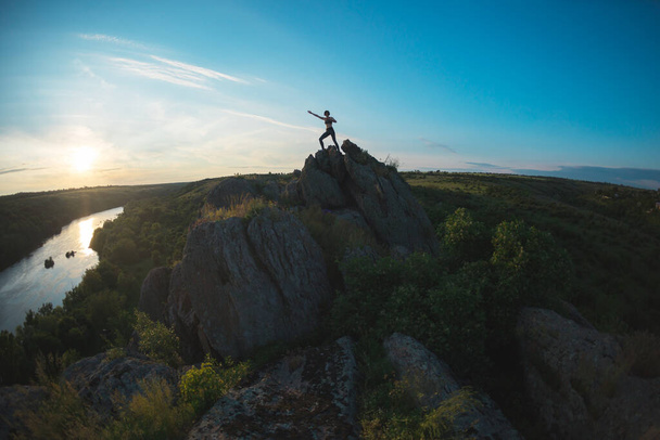 Woman on top of a cliff, silhouette of a girl on top of a mountain, sunset in a beautiful place, travel to picturesque places - Valokuva, kuva