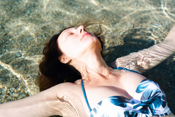 Giovane donna sdraiata sulla schiena sull'acqua nel mare. Godimento della vita e relax. Primo piano. Focus selettivo. - Foto, immagini