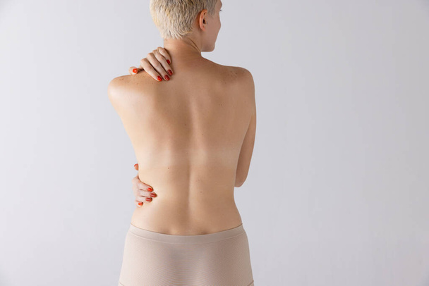 Обрізане зображення тонкого здорового жіночого тіла, спина ізольована на сірому студійному фоні. Модель позування в нижній білизні. Концепція краси, догляду за тілом та шкірою, здоров'я, пластичної хірургії, косметики, реклами
 - Фото, зображення